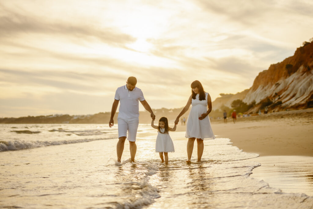 family walking on the beach with feet in the water