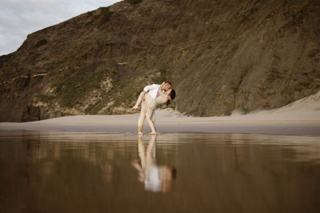 A man holding his fiancé at the beach