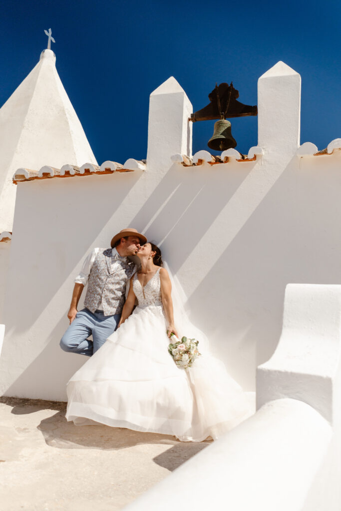 Bride and groom kissing in front of white chapel