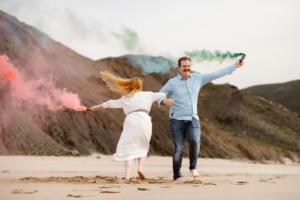 Engagement photo of couple with flairs on the beach