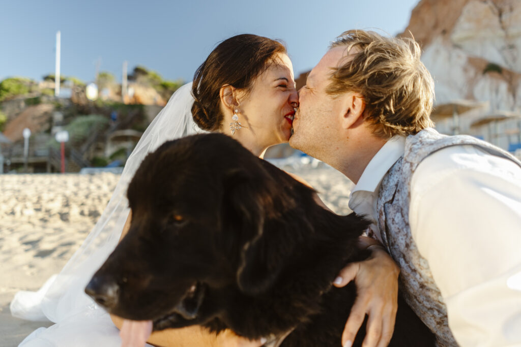 Bride and groom kissing next to their dog