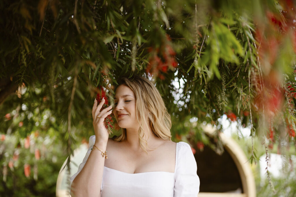 Bride smells flowers on tree in Alvor, Portugal