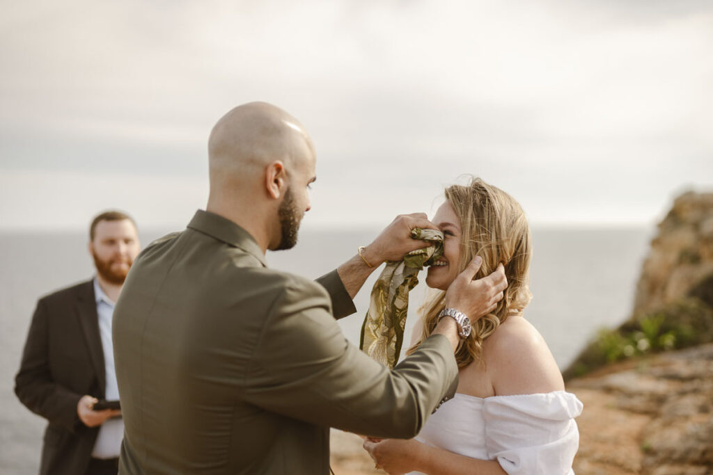 Groom wipes the tears of his bride in Alvor, Portugal