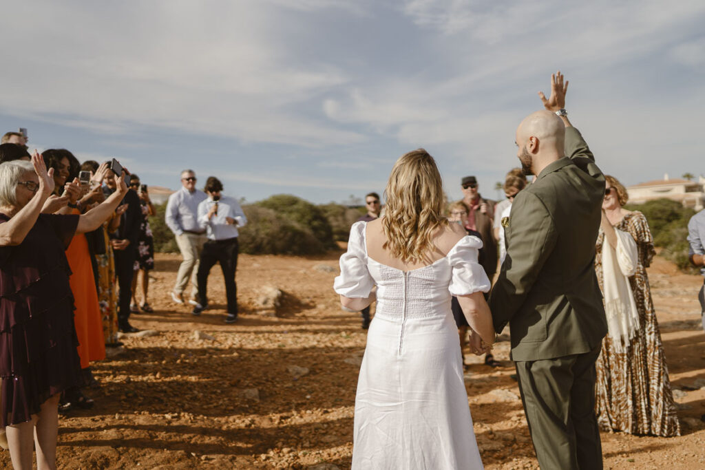 Bride and groom wave to crowd in Alvor, Portugal