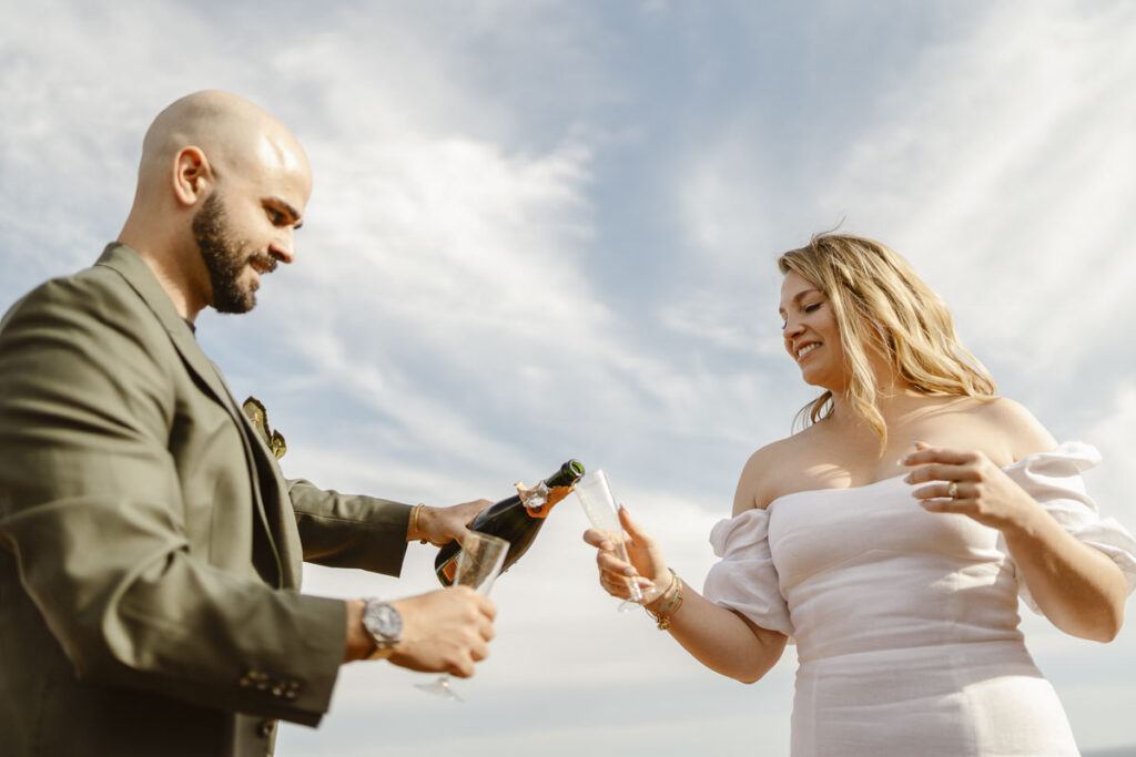 Groom pours champagne into brides glass in Alvor Portugal