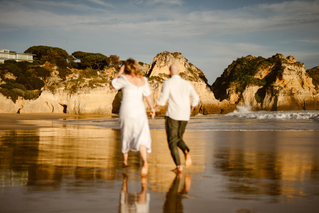 Bride and groom run together on beach in Alvor, Portugal
