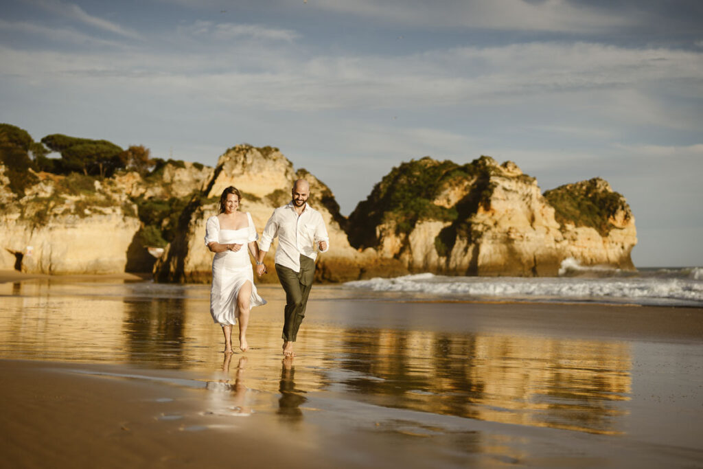Bride and groom run together on beach in Alvor, Portugal
