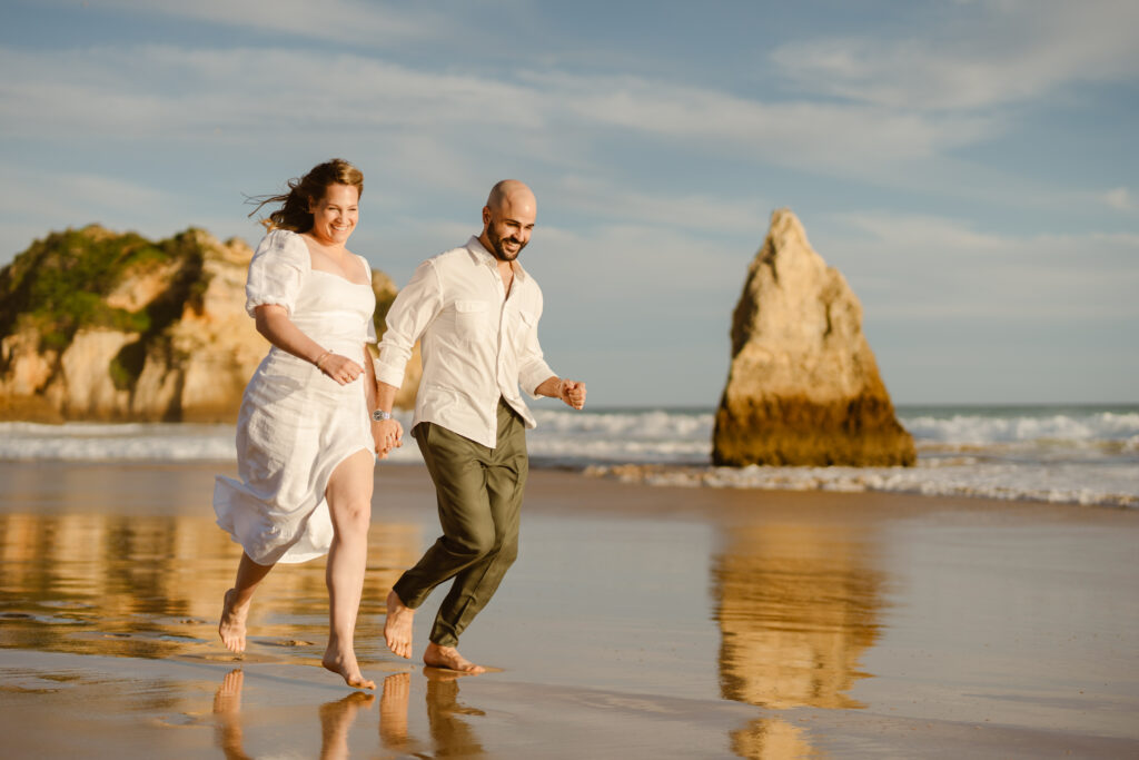 Bride and groom run together on the beach in Alvor, Portugal