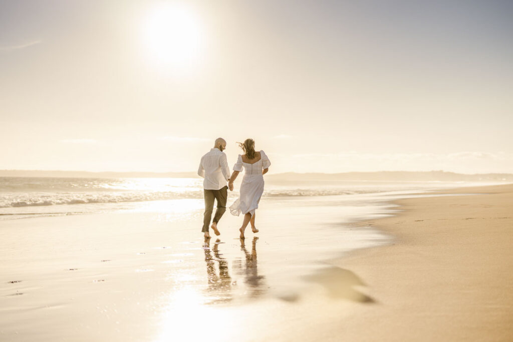 Bride and groom walk together on beach in Alvor, Portugal