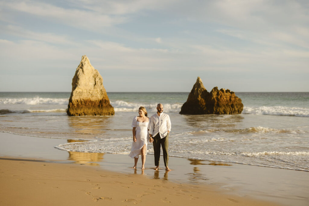 Bride and groom stood on beach while holding hands in Alvor, Portugal