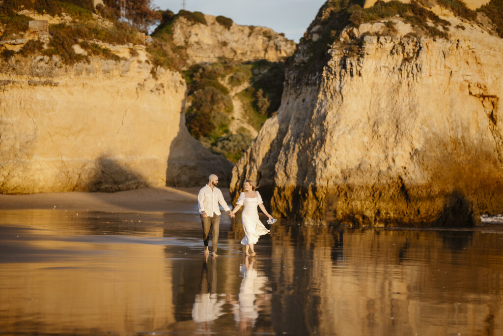 Bride and groom walk on beach in Alvor, Portugal