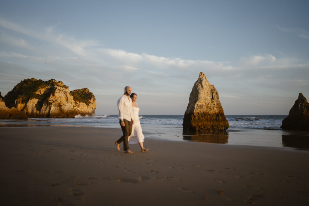 Bride and groom walk down beach together