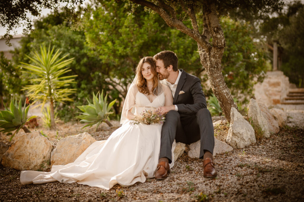 Bride and groom sat in stony garden in Loule, Portugal