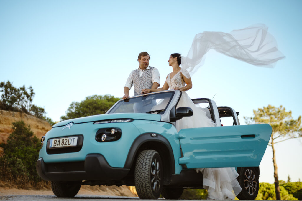 A bride and groom in a blue car