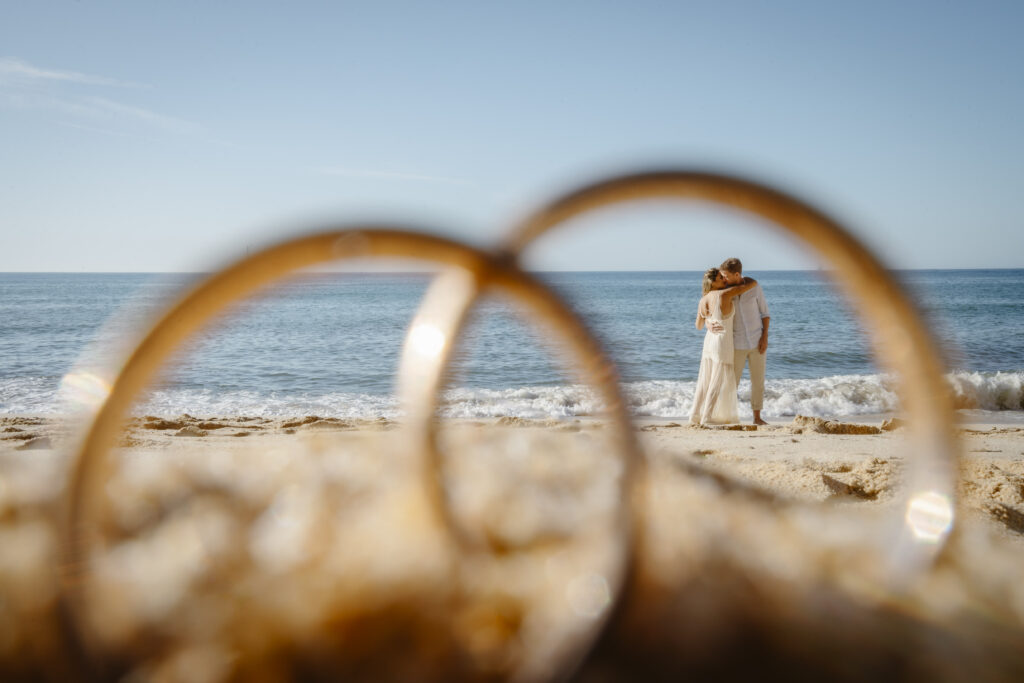 Couple on beach visible through 2 wedding rings