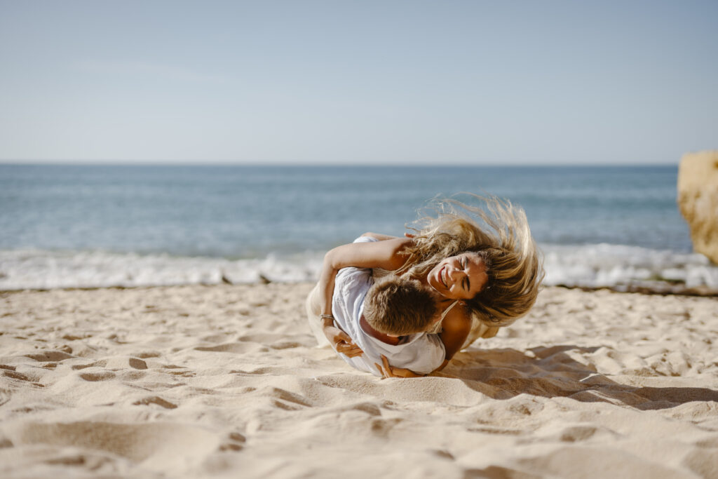 A couple rolling together on the sand