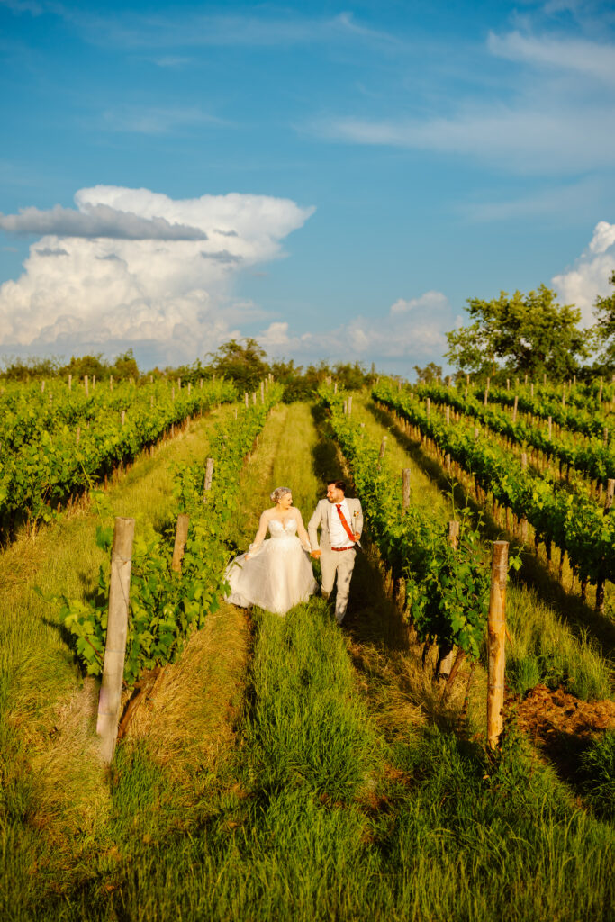 Bride and groom running through a field