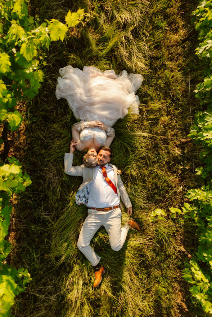 The bride and groom lying on the grass in the vineyard. Elopement in Italy.