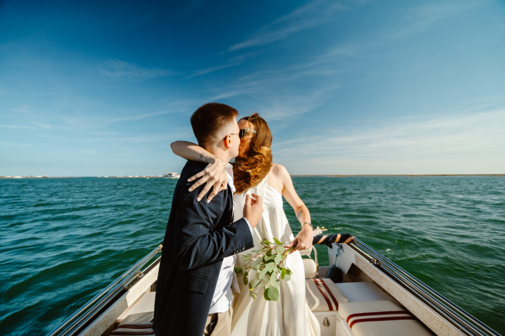 The bride kisses her groom on the speedboat. Elopement in Portugal.