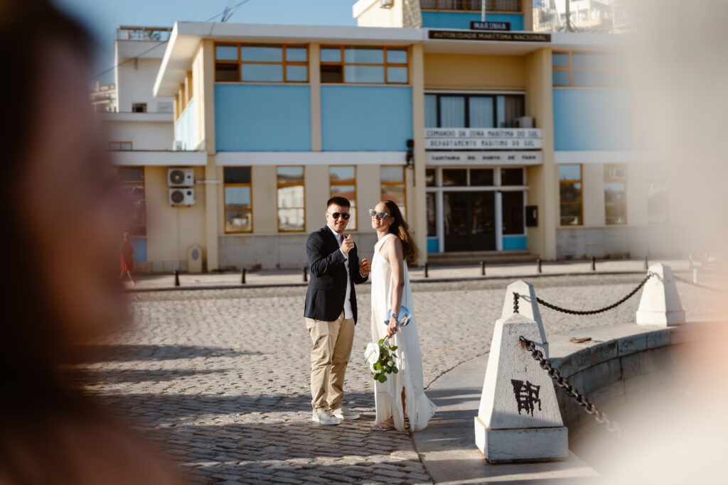 Bride and groom pose near boat dock in Algarve, Portugal