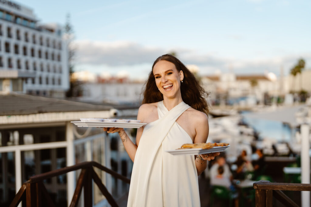 Bride holds plates of food happily in Algarve, Portugal