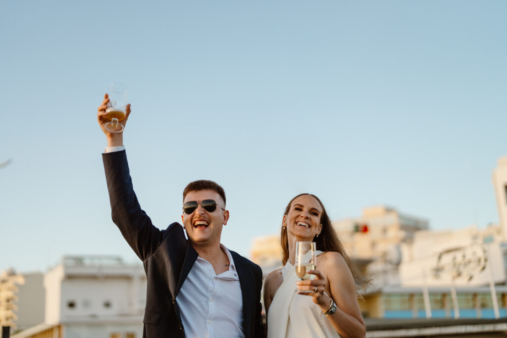 Happy bride and groom make a toast with glass of champagne in Algarve.
