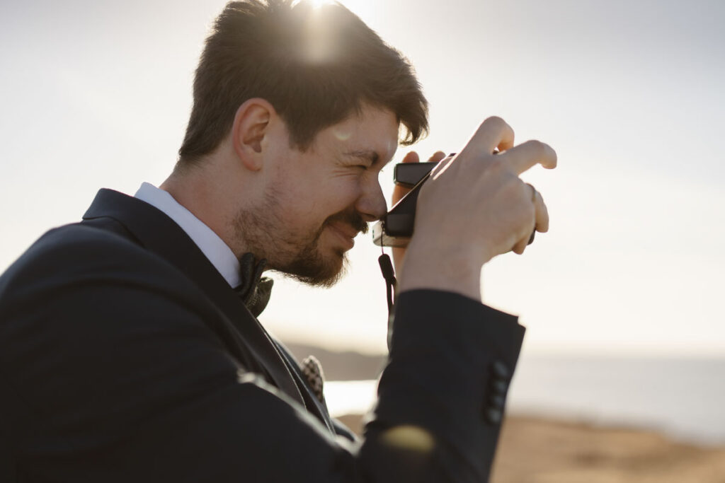 Groom takes photo in Bordeira, Portugal