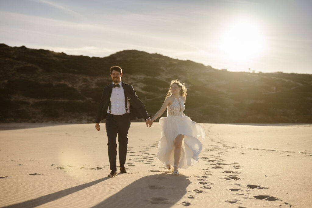 Bride and groom on beach in Bordeira, Portugal