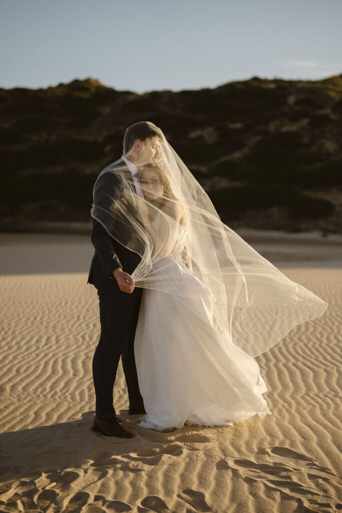 Bride and groom under veil in Bordeira, Portugal