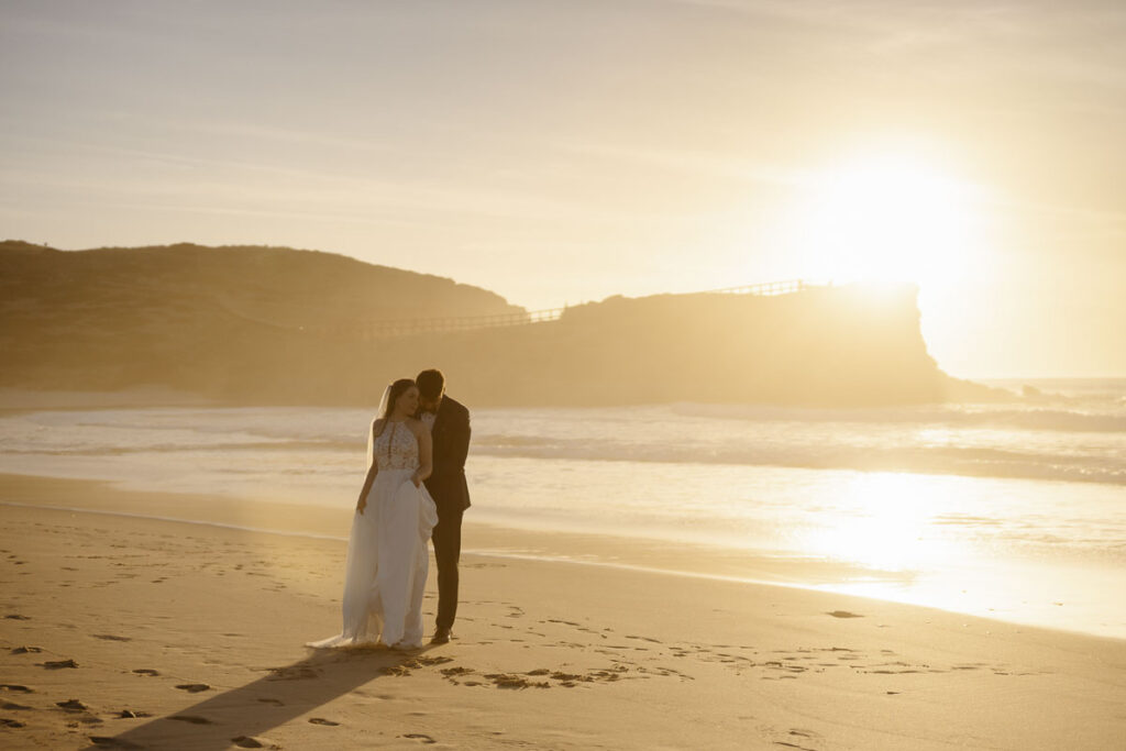 Bride and groom on beach in Bordeira, Portugal