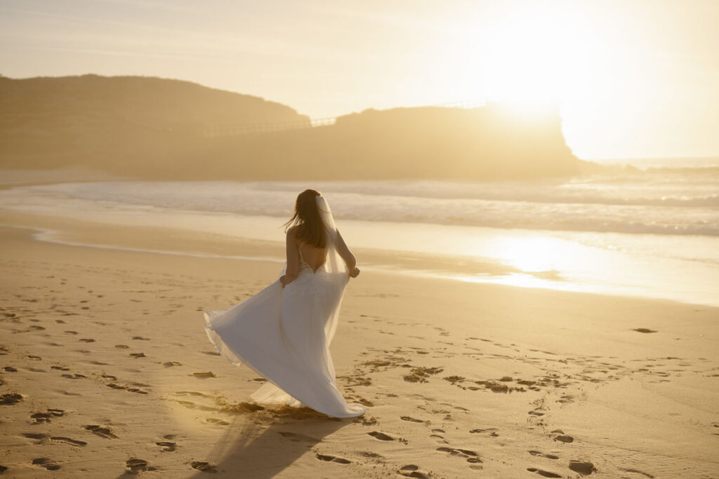Bride walks on beach in Bordeira, Portugal