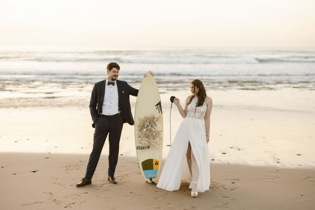 Bride and groom with surfboard in Bordeira, Portugal