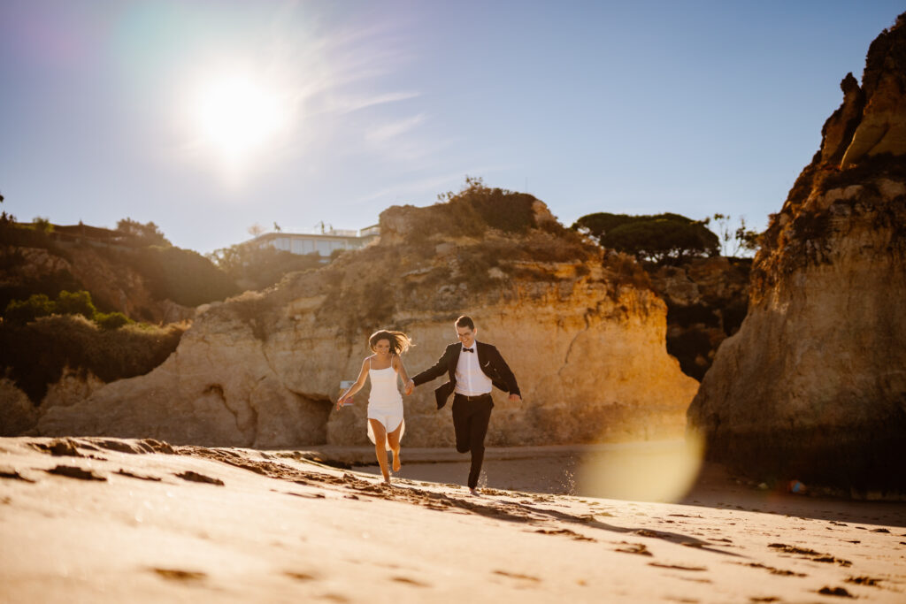 A couple holding hands running on the beach