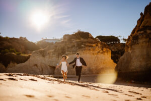 A couple holding hands running on the beach