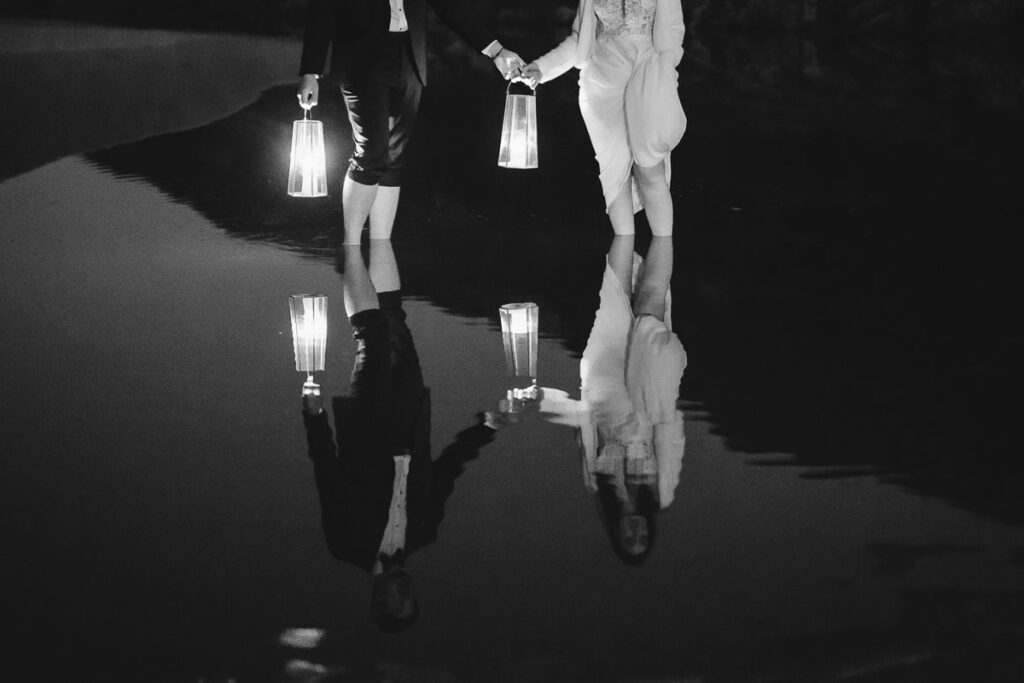 Bride and groom in water with lanterns in Bordeira, Portugal