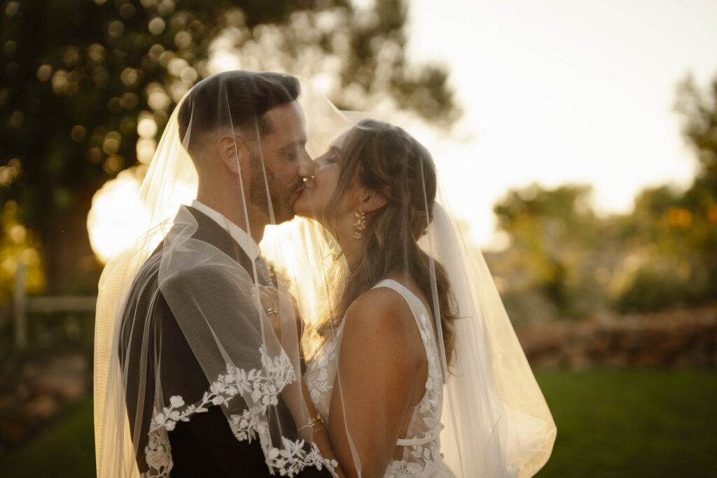 Bride and groom kissing under veil