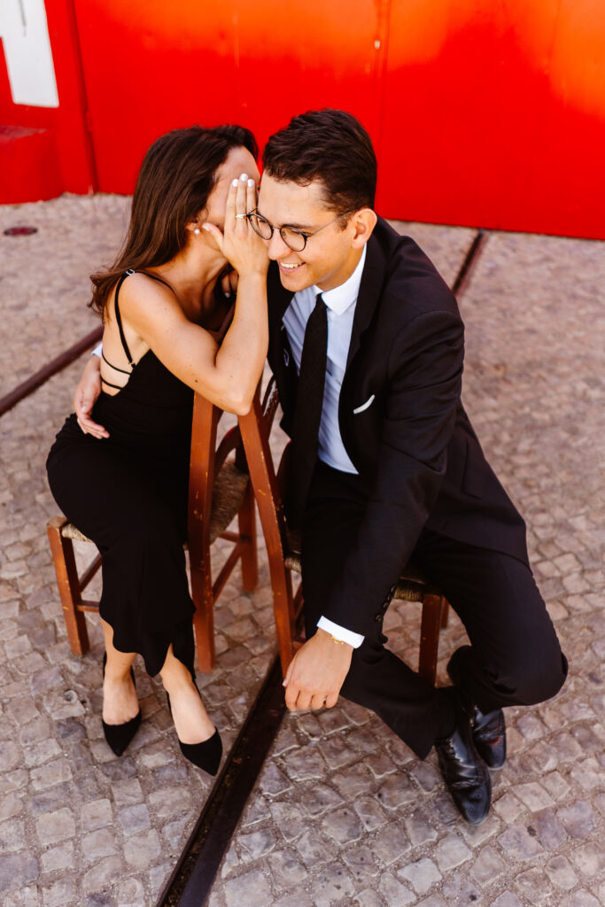 A woman whispering into her fiancés ear
