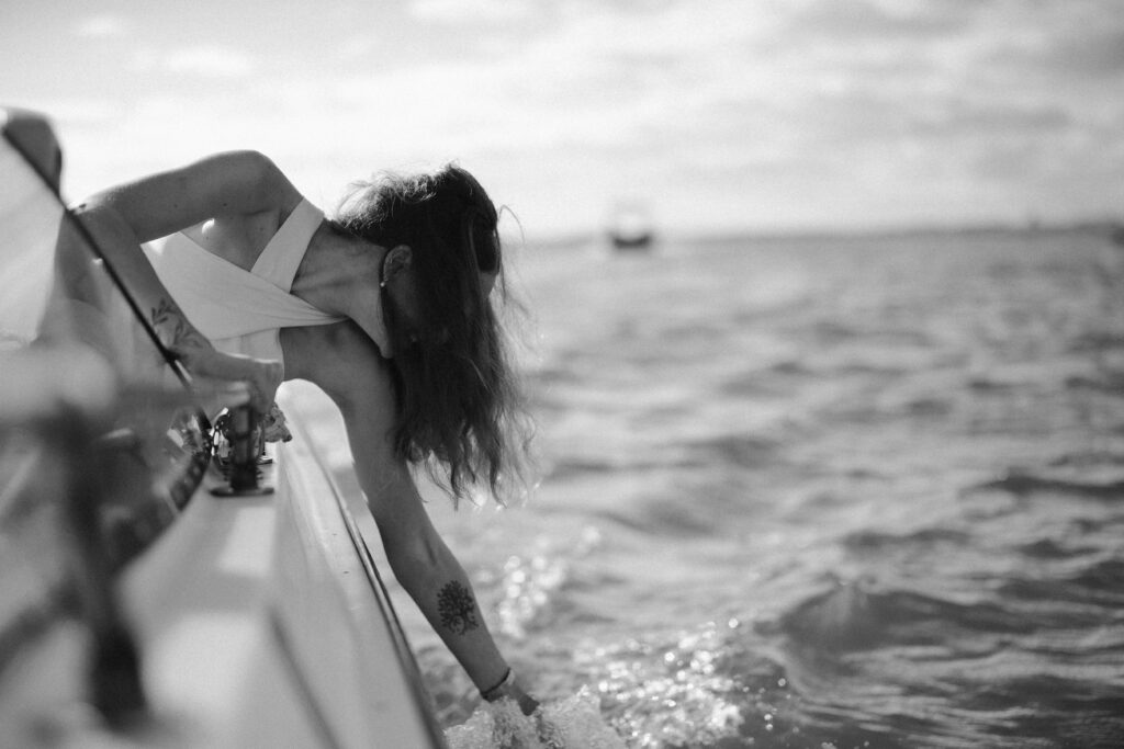 Bride lowers hand to water on boat in Algarve, Portugal