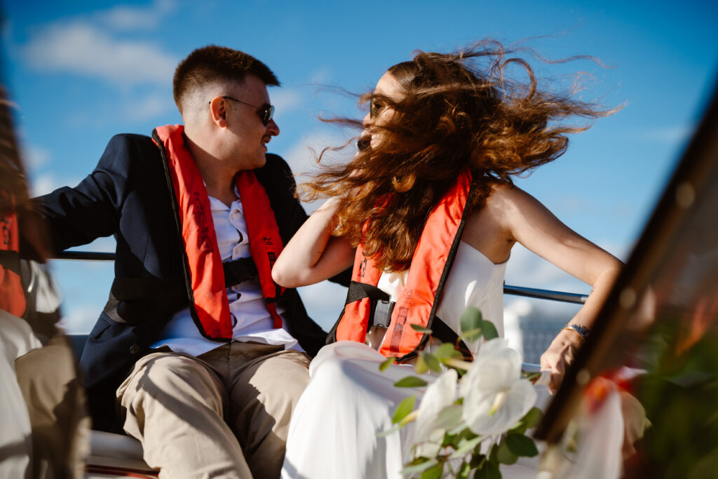 Bride and groom wear life jackets while in boat in Algarve, Portugal
