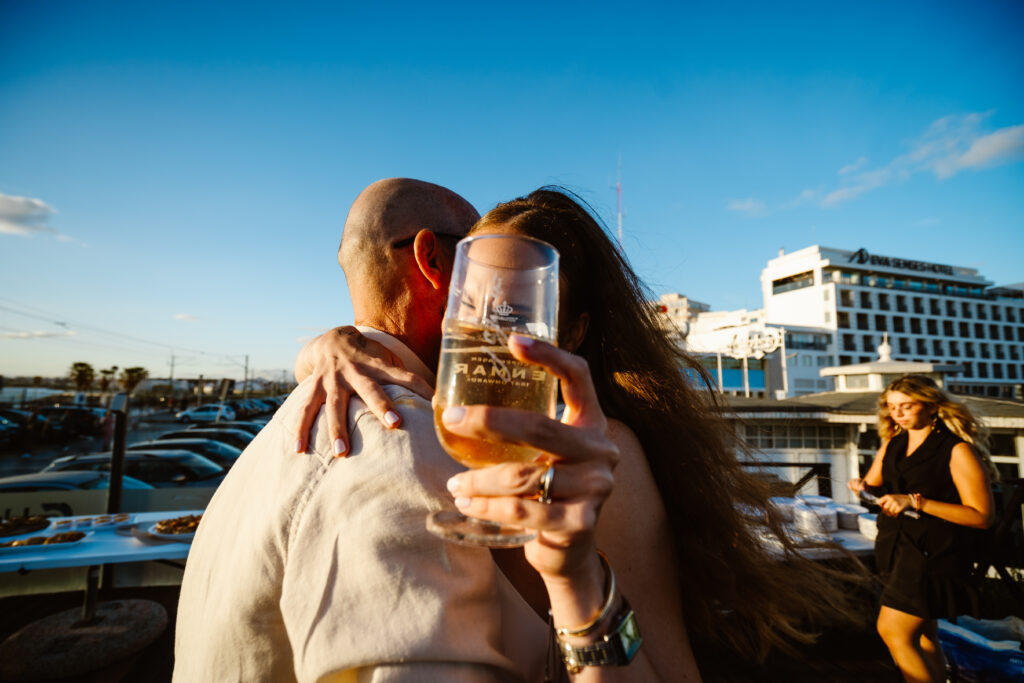 Bride hugs man with a beer in Algarve, Portugal