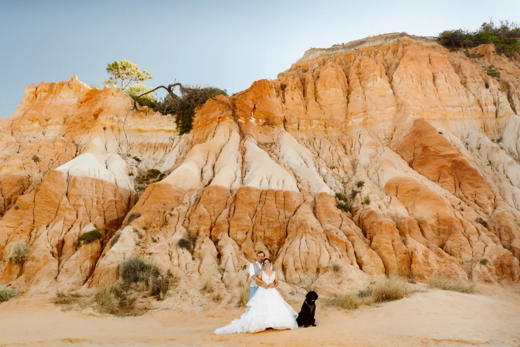 Bride and groom eloping at red cliffs of Algarve, Portugal during golden hour