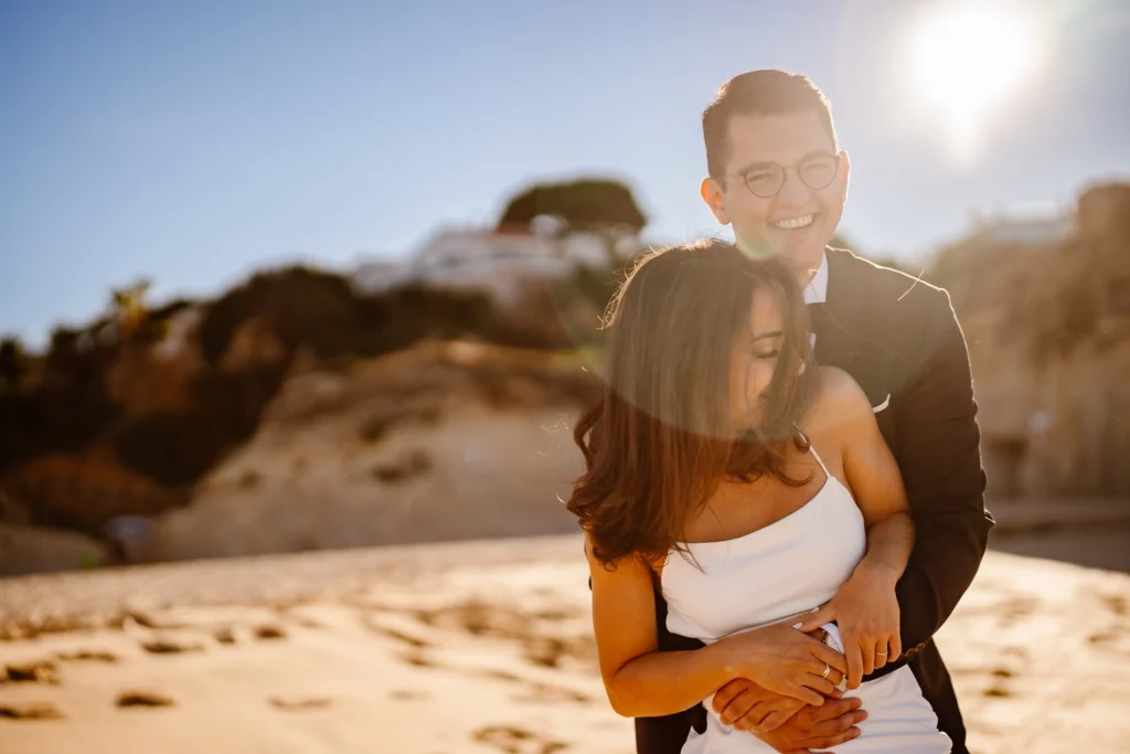 Sun-kissed couple embracing on Algarve beach after ceremony
